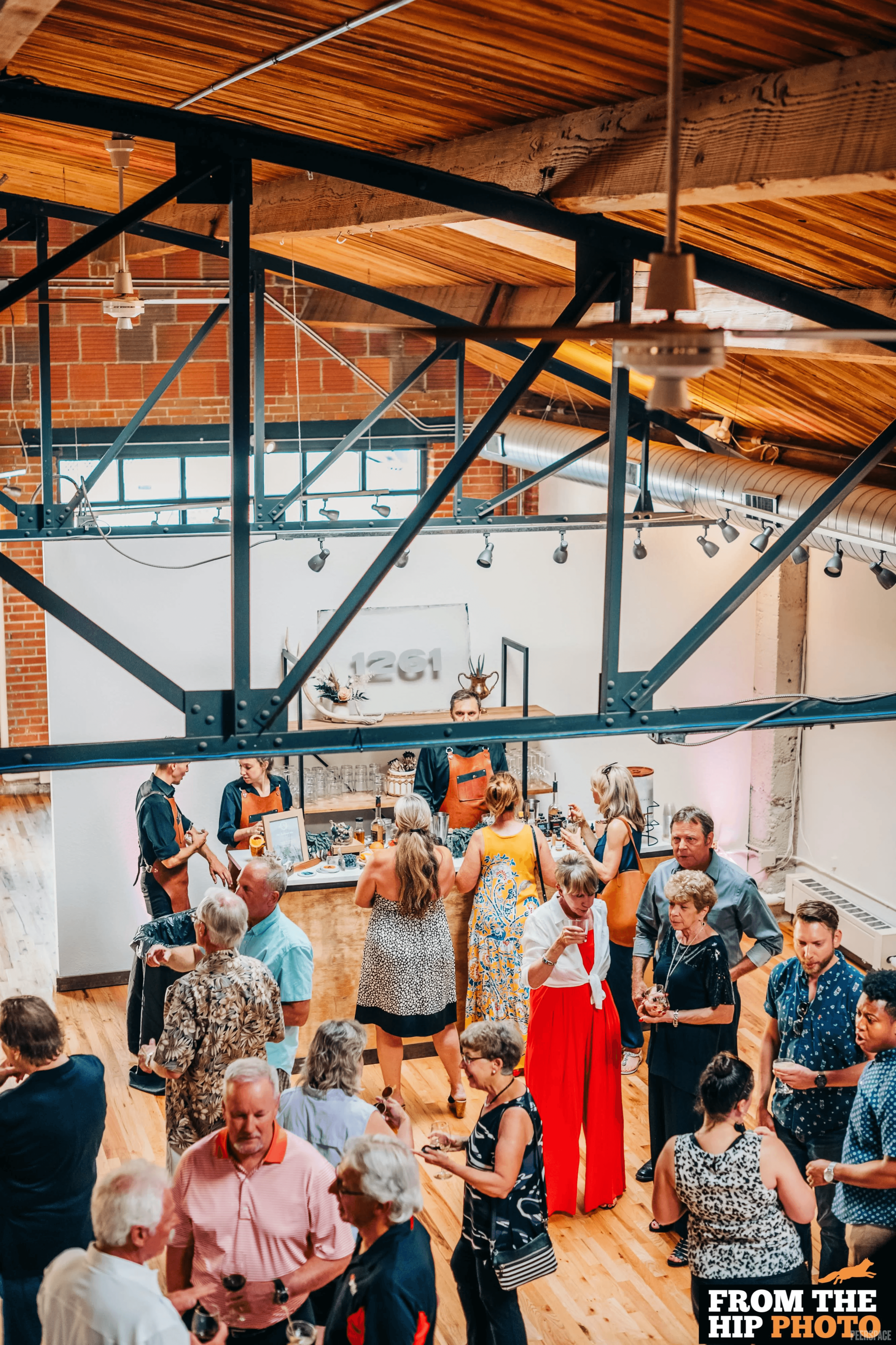 Cocktail party at Sterling Event Space — guests, steel trusses, and the 1261 bar in Denver's Golden Triangle