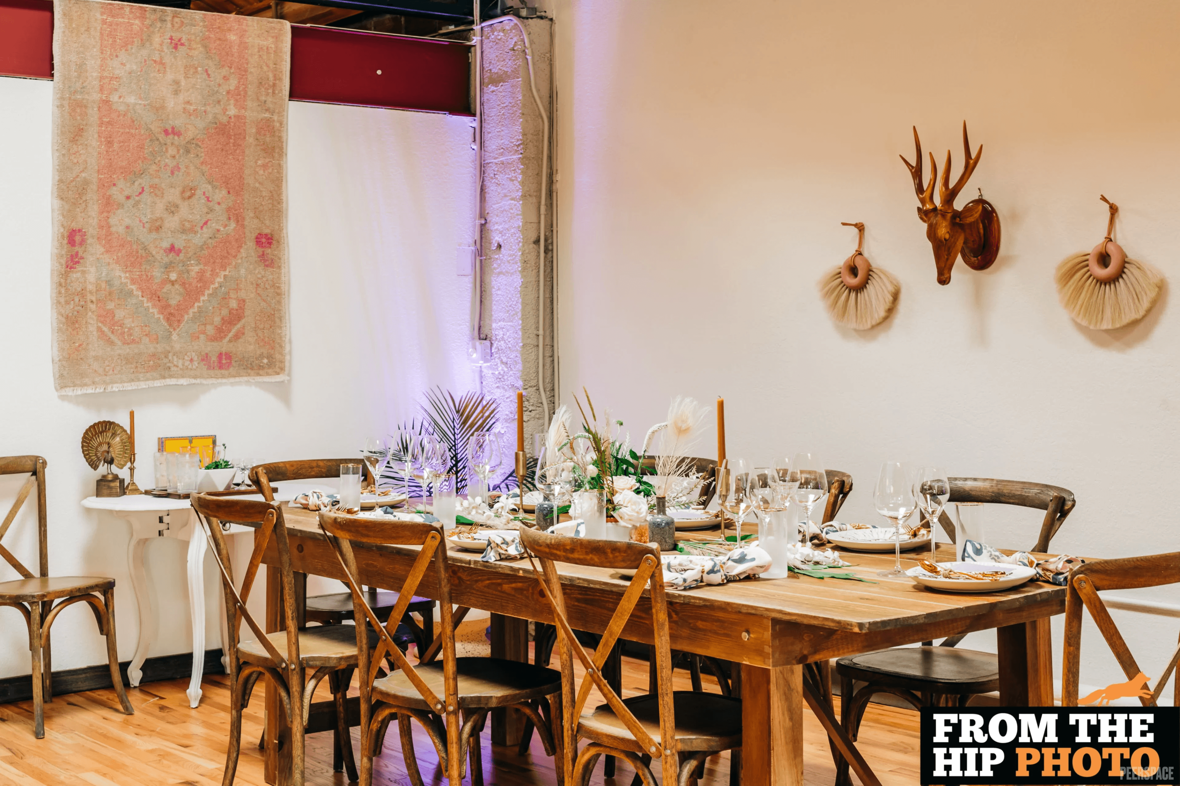 Long farm-table dinner at Sterling Event Space with hanging tapestries and cross-back chairs