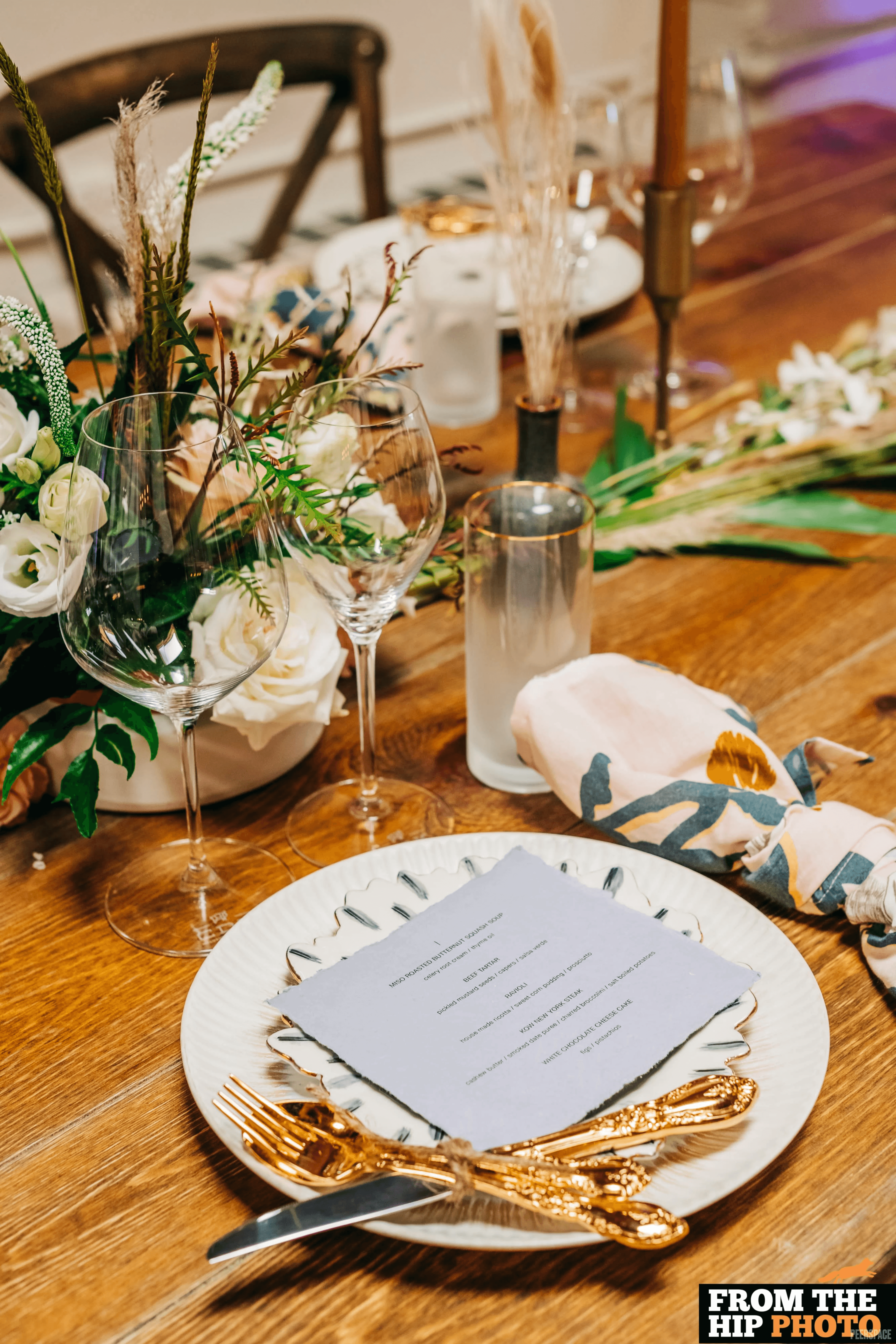 Wedding tablescape detail — white florals, gold cutlery, candles
